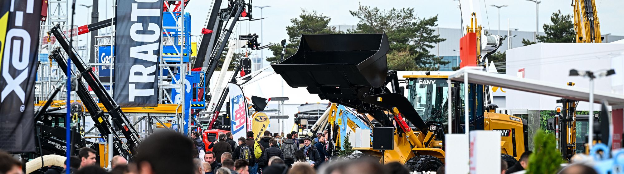 Salon professionnel du BTP avec machines de construction, grues et engins exposés en extérieur avec visiteurs