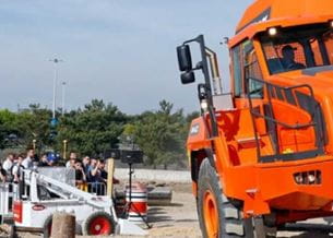 Groupe de personnes regardant une démonstration d'une machine de construction orange 